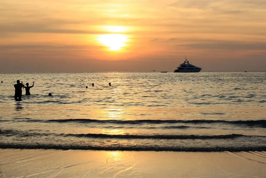 Bagno in mare al tramonto con una barca all'ancora