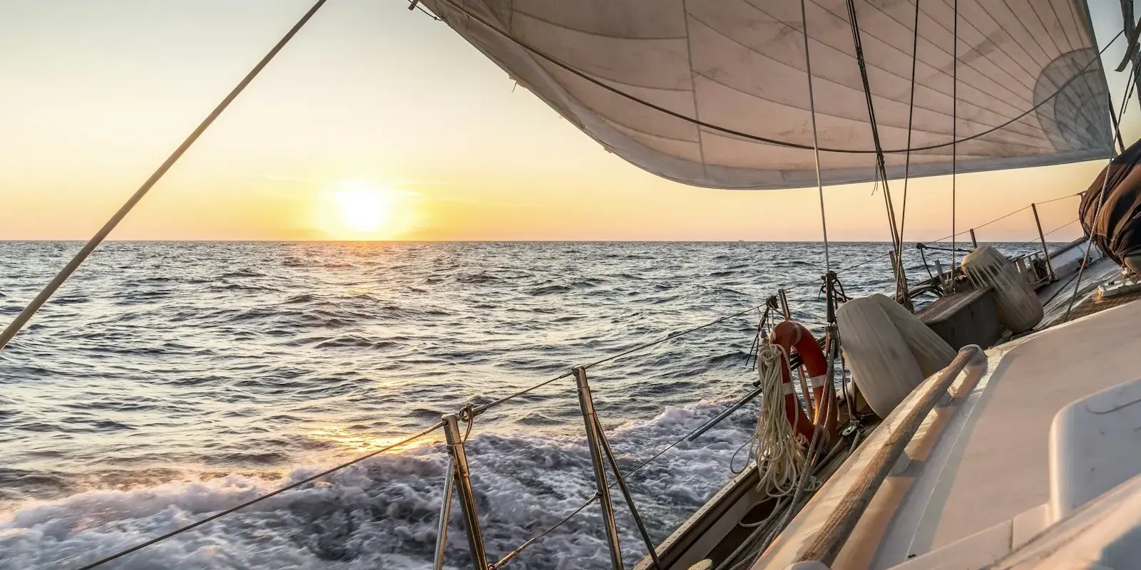 Il ponte di una barca a vela verso il sole al tramonto